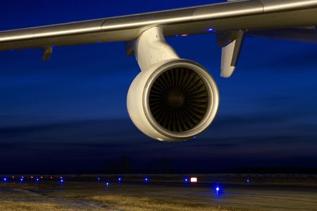 Aircraft wing with engine near night runway.の写真素材