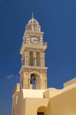 High church tower with clocks and cross on the top of this. Santorini, Fira, Greece.の写真素材