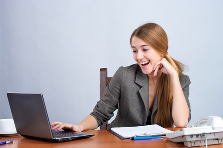 Portrait of happy young business woman working on laptop in the officeの写真素材