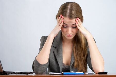 Tired female employee sitting at her desk in officeの写真素材