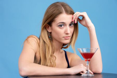 Beautiful young woman with cocktail glass against blue backgroundの写真素材