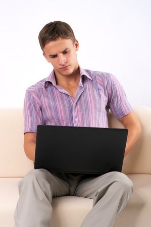 Young man working on his laptop on the sofa at homeの写真素材