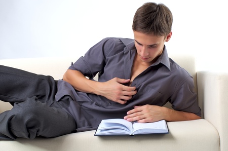 Young man reading book on the sofa at homeの写真素材