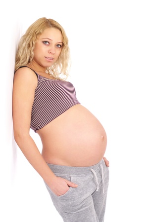 Beautiful young pregnant woman standing at the white wallの写真素材