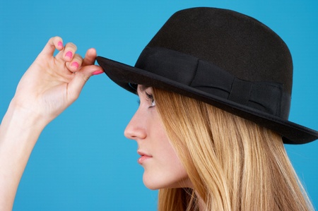 Closeup portrait of beautiful young woman in black hat against blue backgroundの写真素材