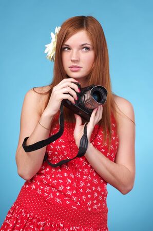 Young photographer woman holding camera against blue backgroundの写真素材