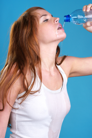 Beautiful young woman drinks water from bottle after fitness exerciseの写真素材