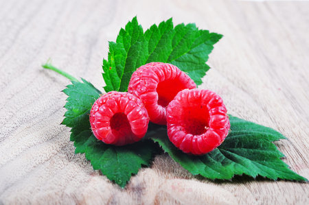 Raspberries on a leaf on a wooden board