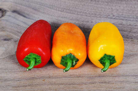 Red, orange and yellow pepper on a wooden boardの写真素材