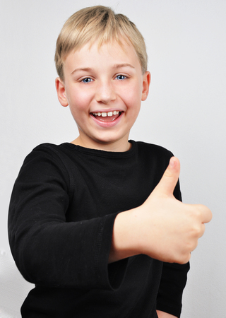 Cute little boy laughing and with a thumb up. Studio shot.の写真素材