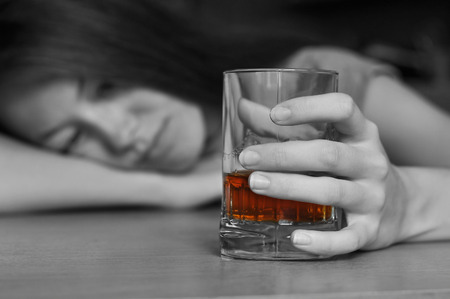 Young drunk woman holding a glass of whiskeyの写真素材