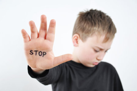 Small abused boy holding his hand with the word 'STOP' written on it. Concept of domestic violence...