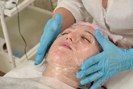 Young woman in beauty salon doing peeling and facial cleansing procedure. Cosmetic multifunctional device. Ultrasound procedure. Medical equipment healthcare. Face professional massage.の写真素材