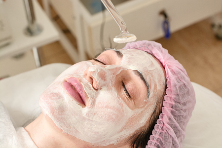 Young woman in beauty salon does rejuvenating, toning procedure darsonval on the face. Medical beauty equipment healthcare. Close-up beauty procedure. Modern darsonval's beauty procedure.の写真素材