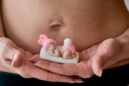 Pregnant young woomen holds a figurine of soap in the shape of a newborn baby girl in front of her...