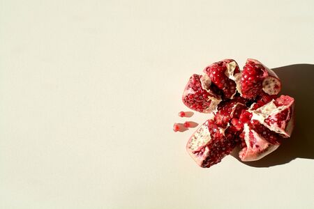 Garnet. Ripe red juicy pomegranate. Grains pomegranate fruit. Pomegranate cut in the form of a star. Lonely fruit on a light background. Hard daylight.の写真素材