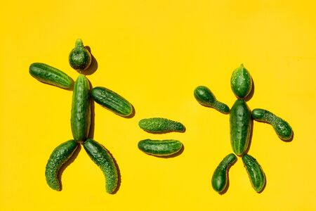 People equality diversity concept on a yellow background. Copy space. Cucumbers for designers. Top view. Cucumber harvest. Cucumber men. Figure of men made from cucumbers. Farming harvesting concept.の写真素材