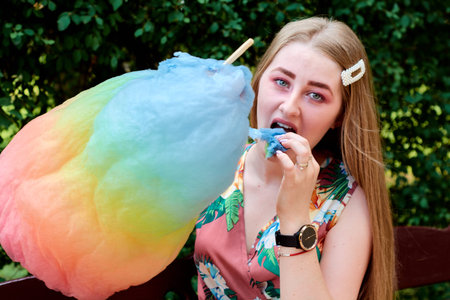 Happy joyful beautiful young woman with candy floss in the park at summer.