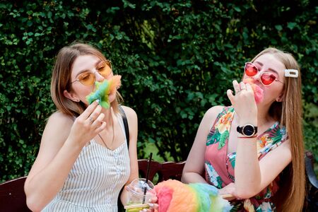 Two happy beautiful young sexy lesbian women with candy floss, spun sugar, cotton candy in the summer park. Summer time events. Summer vacation. Vacation time. Free love concept. Girlfriends day.の写真素材