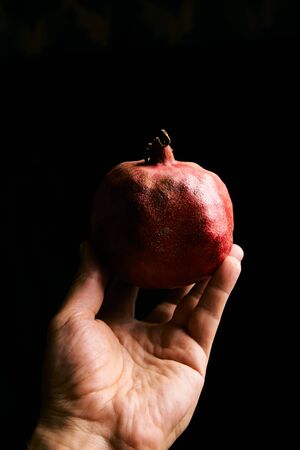 Fresh garnet in the man hand isolated on the black background with copyspase for cards and design for healthy life. Pomegranate.の写真素材