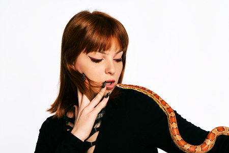 Beautiful woman in black bodywear and snake. Ginger model girl with fashion perfect make up.