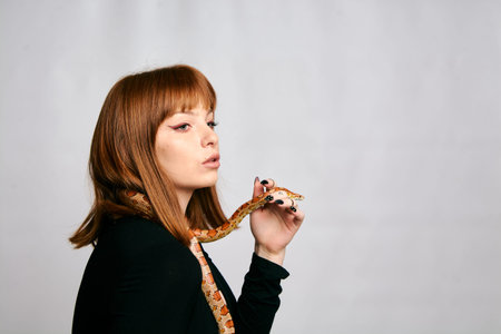 Beautiful woman in black bodywear and snake. Ginger model girl with fashion perfect make up.