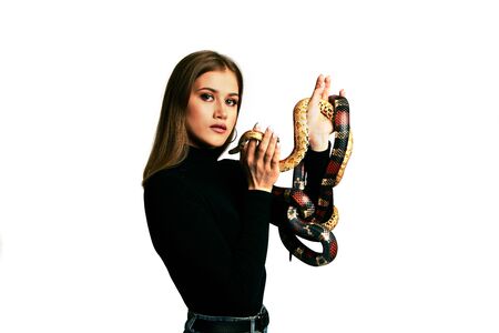 Beautiful woman in black bodywear and snake. Blonde model girl with fashion perfect make up. High end retouch. White background. Young woman with perfect fresh skin. Woman with snake around her face.の写真素材