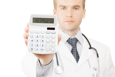 Medical doctor isolated on white with a calculator in his right hand showing calculated costs and revenues in physician practice and hospital feesの写真素材