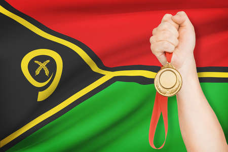 Sportsman holding gold medal with flag on background - Vanuatuの写真素材