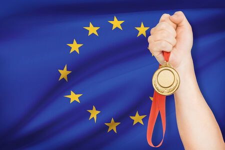 Sportsman holding gold medal with flag on background - European Unionの写真素材