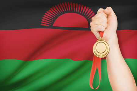 Sportsman holding gold medal with flag on background - Republic of Malawiの写真素材