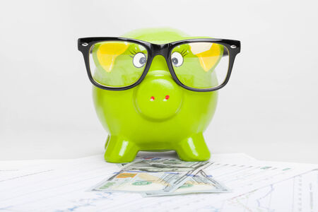 Green piggy bank over stock market chart with 100 dollars banknoteの写真素材