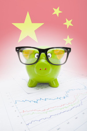 Piggy bank over stock market chart with Chinese flag on background - part of seriesの写真素材