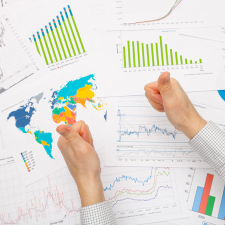 Business man working with financial data - thumbs up - focus on graphs - studio shot