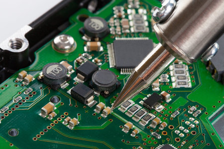 Studio shot of soldering iron and microcircuit