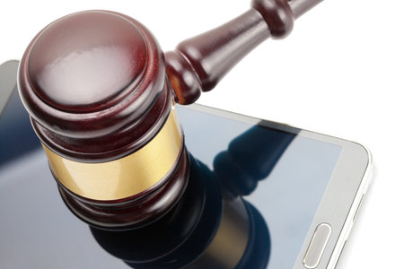 Smartphone under judge gavel over it - studio shot on white
