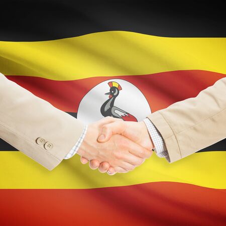Businessmen shaking hands with flag on background - Ugandaの写真素材