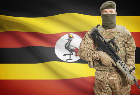 Soldier holding machine gun with national flag on background - Ugandaの写真素材