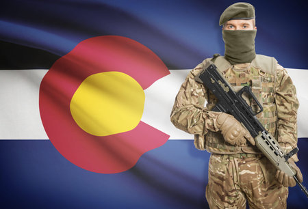 Soldier holding machine gun with USA state flag on background - Colorado