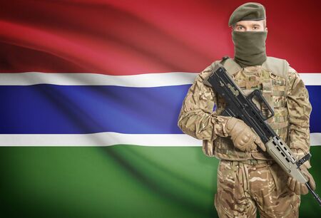 Soldier holding machine gun with national flag on background - Gambiaの写真素材