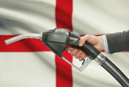 Fuel pump nozzle in hand with flag on background - Englandの写真素材