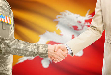 American soldier in uniform and civil man in suit shaking hands with national flag on background - Bhutanの写真素材