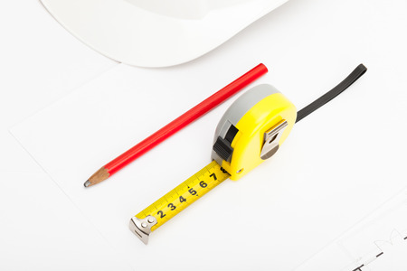 White construction helmet with pencil and yellow measure tape near itの写真素材