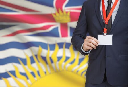 Businessman holding name card badge on a lanyard with Canadian province flag on background - British Columbiaの写真素材