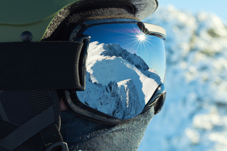 Ski goggles with reflection of snowed mountains in it