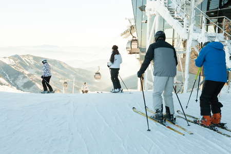 Skiers and snowboarders making downhill ride from the very top of a mountainの写真素材