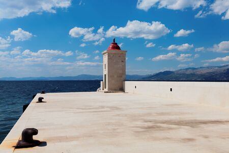 Lighthouse in the harbor of a small town during daytime - Croatia, Brac islandの写真素材