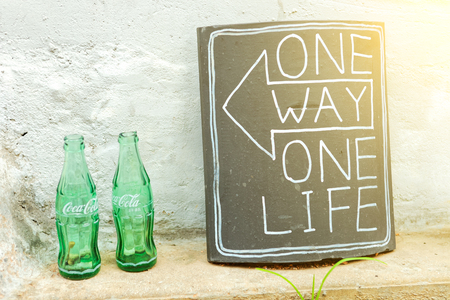 SEOUL, KOREA - AUGUST 09, 2015: Empty bottles of Coca-Cola next to ceramic plate with words "One way, One life" next to it - Seoul, South Koreaのeditorial素材