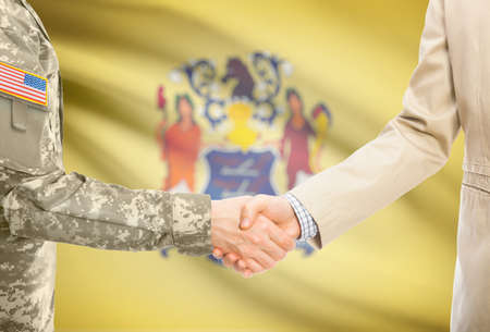 American soldier in uniform and civil man in suit shaking hands with certain USA state flag on background - New Jerseyの写真素材