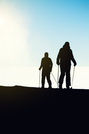Two skiers getting reading ready for downhill ride from the very top of a mountain - outdoors shotの写真素材